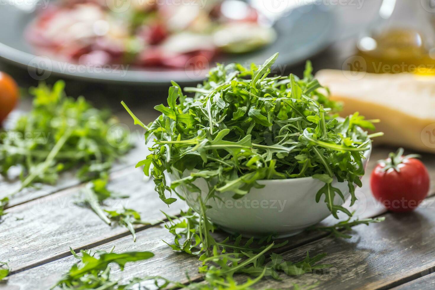 fresco rucola insalata nel bianca piatto su di legno tavolo foto