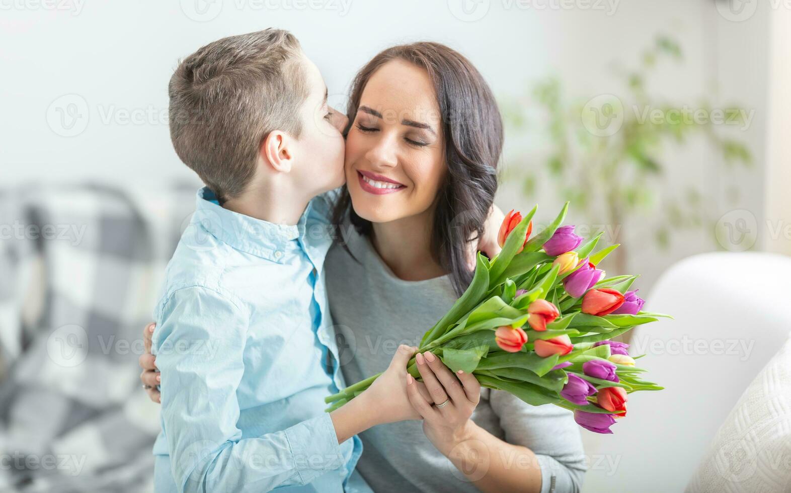 giovane madre ricevente un' mazzo pieno di tulipani e un' esageratamente bacio a partire dal il suo figlio durante nazionale madri giorno foto