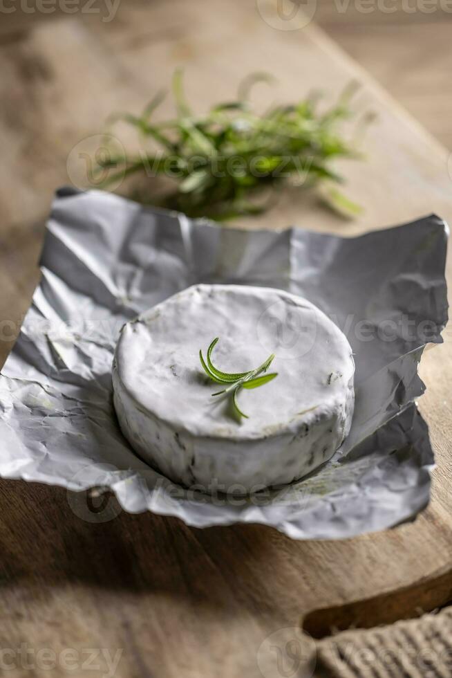 ha aperto pacchetto di Brie formaggio con un' primavera di rosmarino su superiore con un' rustick sfondo foto