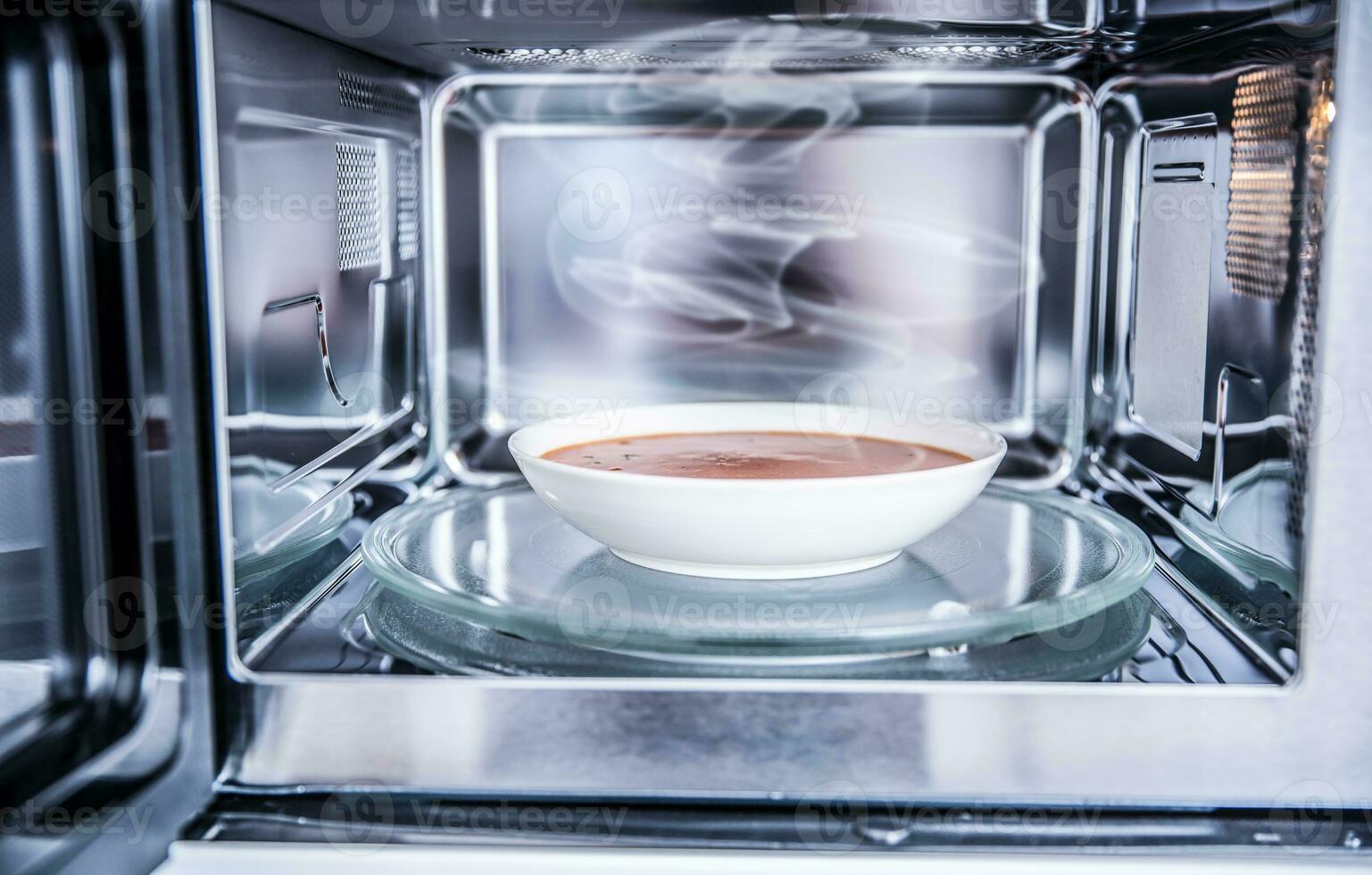 dentro Visualizza di nuovo pulito instancabile microonde forno con un' pomodoro la minestra nel bianca piatto foto
