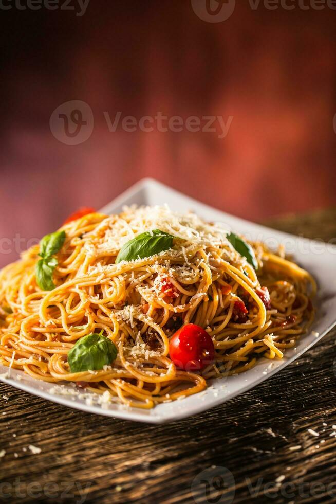 italiano pasta spaghetti con pomodoro salsa basilico e parmigiano formaggio nel bianca piatto foto