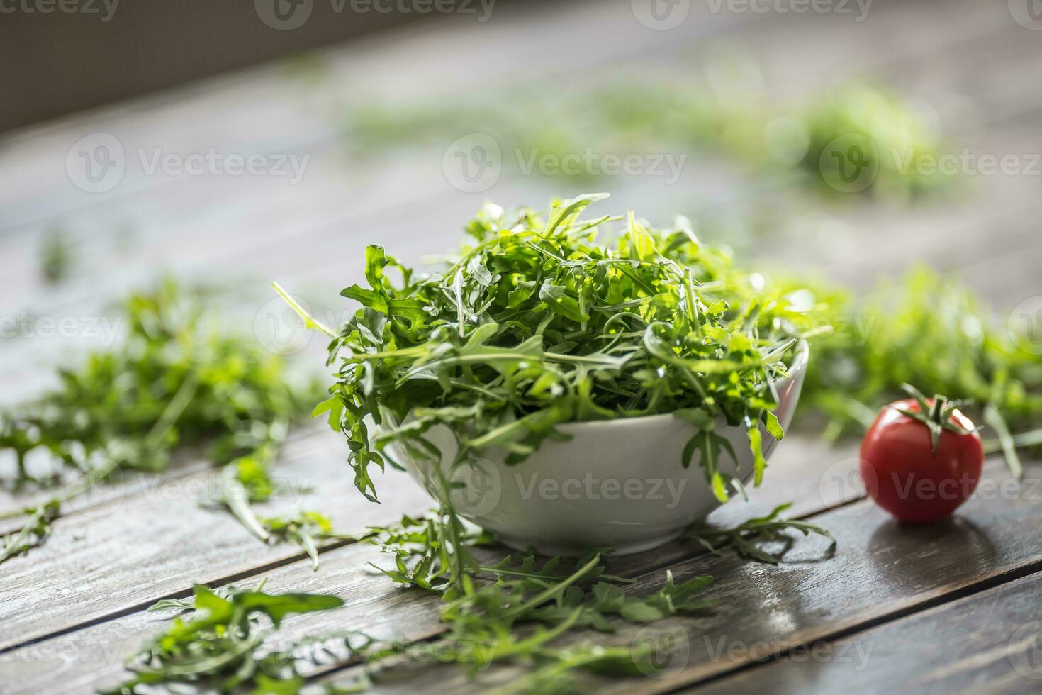 fresco rucola insalata nel bianca piatto su di legno tavolo foto