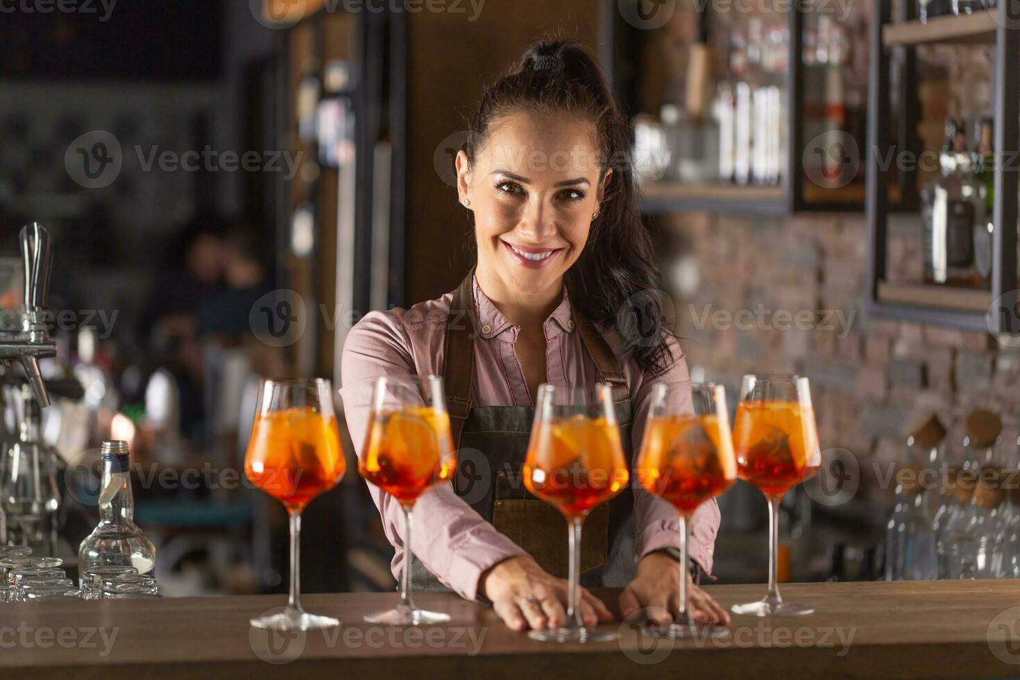 bellissimo barista servi cinque arancia cocktail nel vino bicchieri su un' bar foto