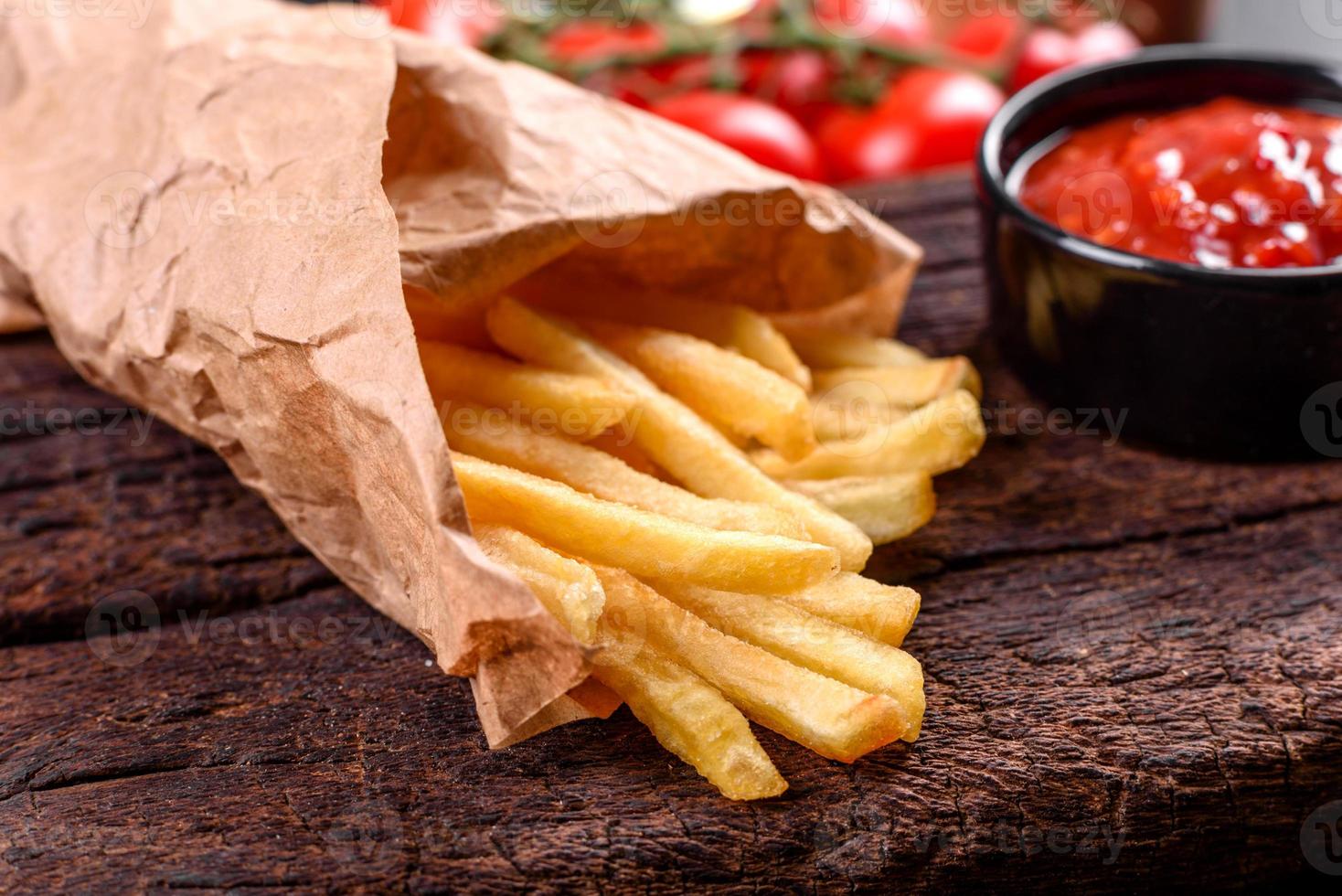 patatine fritte fresche e gustose e salsa rossa su un tagliere di legno foto