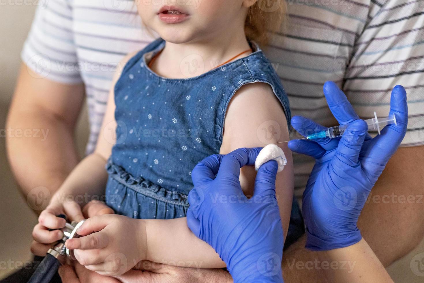 una bambina con suo padre nell'ambulatorio della clinica viene vaccinata contro il coronavirus foto