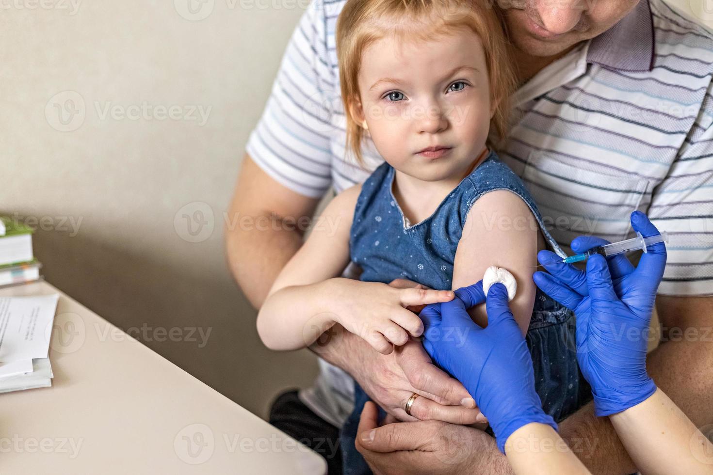 una bambina con suo padre nell'ambulatorio della clinica viene vaccinata contro il coronavirus foto