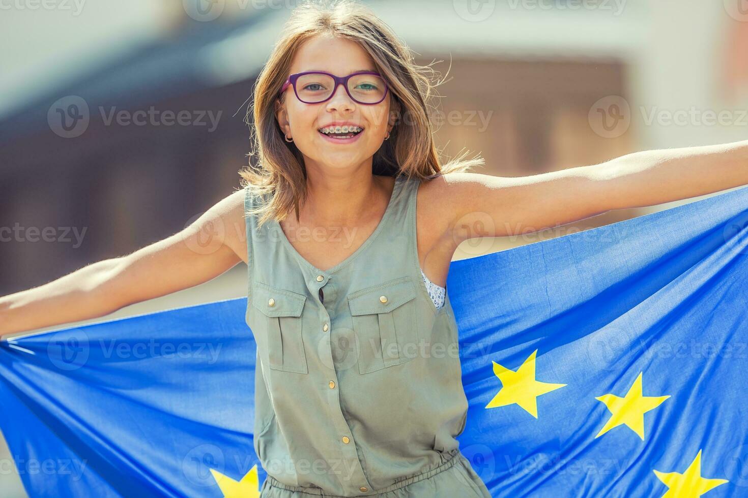 Unione Europea bandiera. carino contento ragazza con il bandiera di il europeo unione. giovane adolescenziale ragazza agitando con il europeo unione bandiera nel il città foto