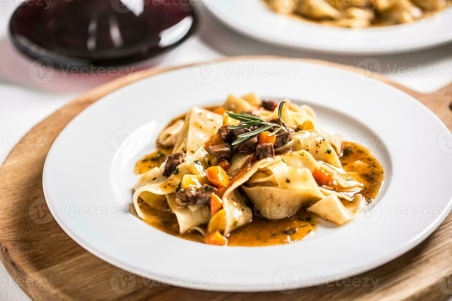 idaliano pasta pappardelle con Manzo ragù su bianca piatto e rosso vino foto