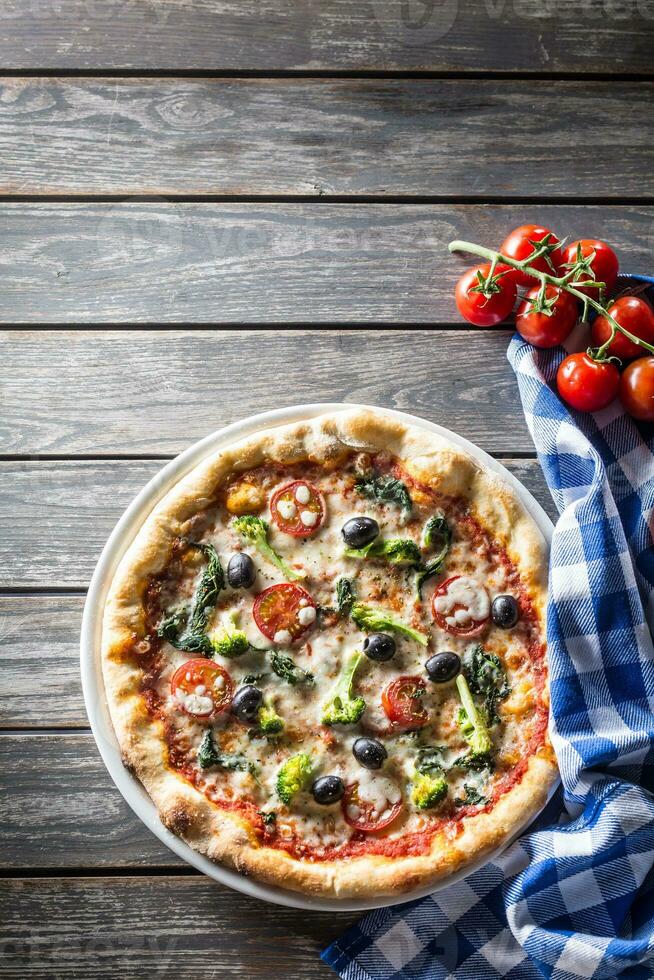 italiano Pizza con broccoli spinaci pomodori olive e mozzarela o parmigiano formaggio. mediterraneo vegetariano pasto foto