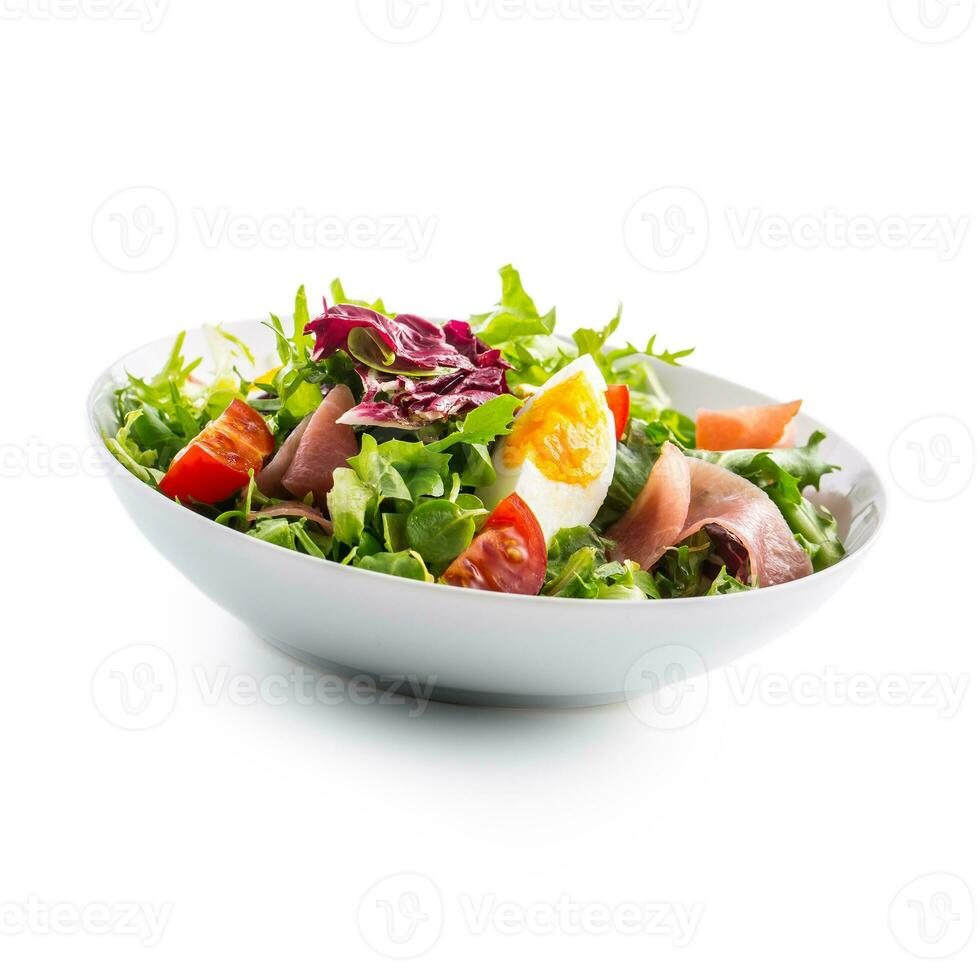 insalata isolato su bianca. un' ciotola di fresco lattuga insalata con pomodori uova prosciutto al di sopra di bianca foto
