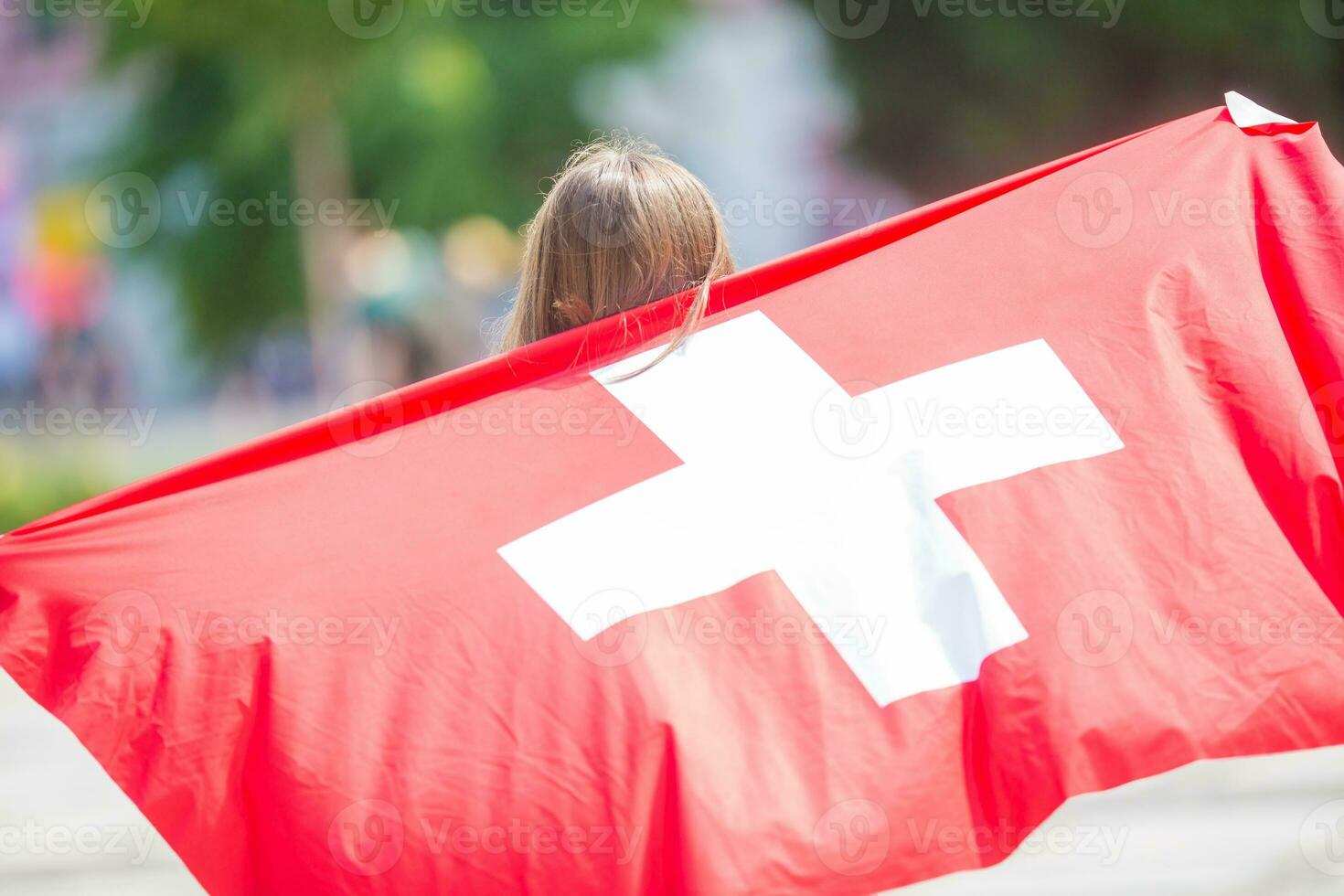 contento ragazza turista a piedi nel il strada con Svizzera bandiera foto