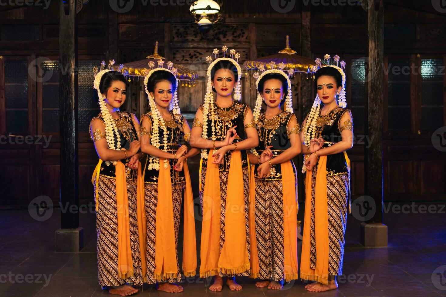 un' gruppo di giavanese ballerini in piedi con loro amici mentre indossare giallo costumi e scialli foto