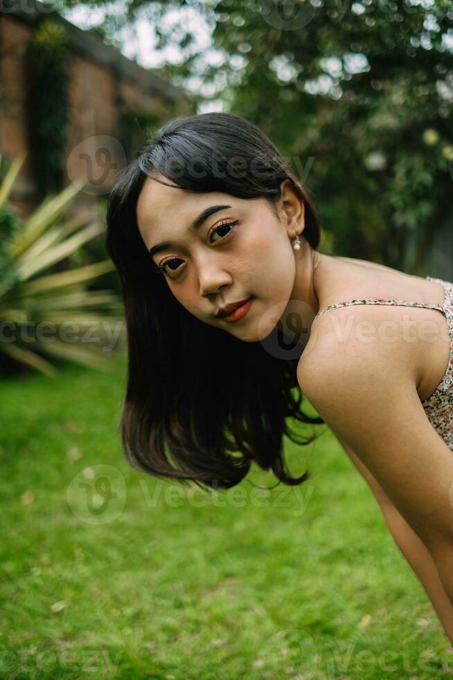 ritratto di un indonesiano donna con Riccio braccia e nero capelli indossare un' sexy stampato vestito foto