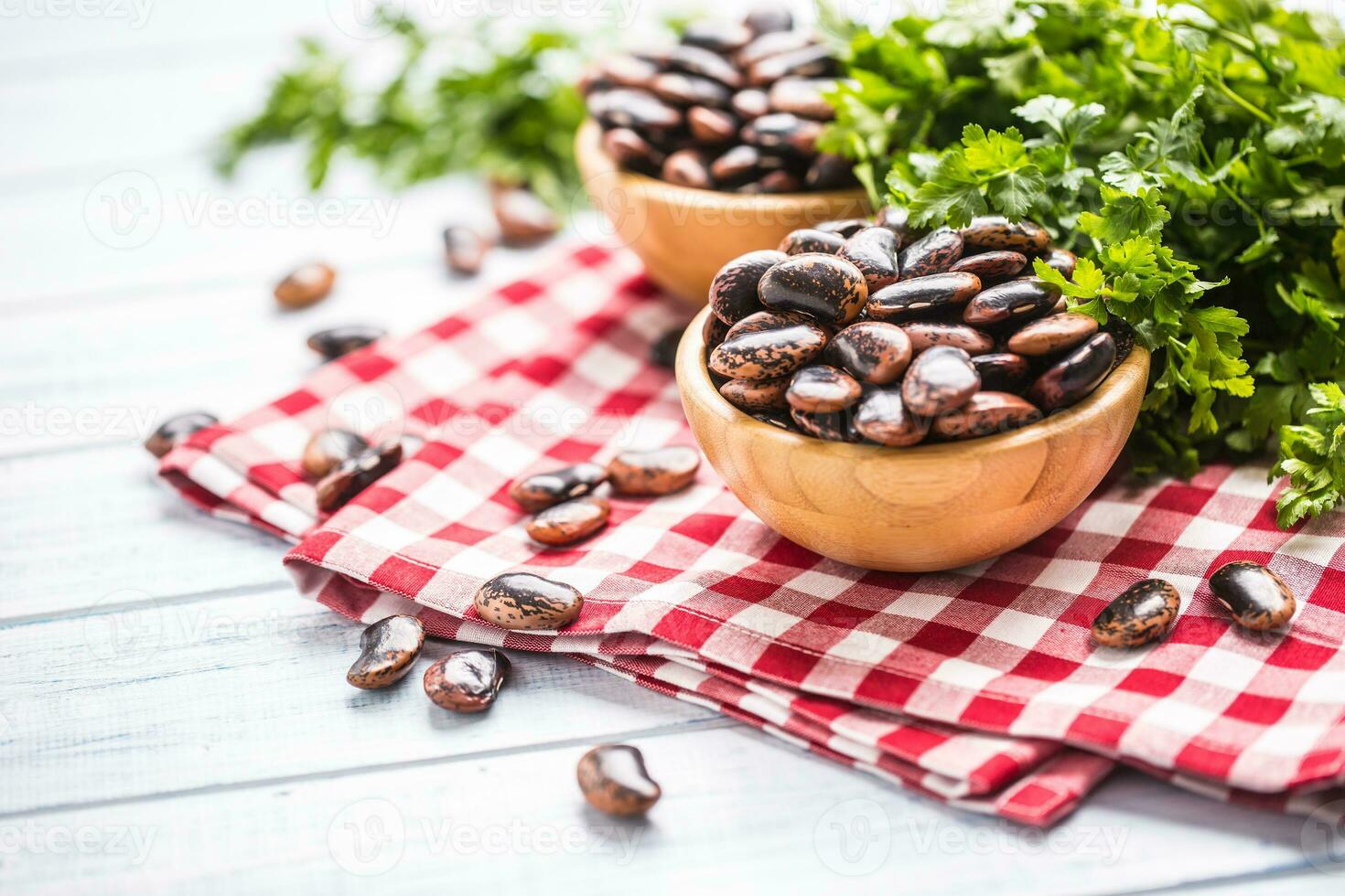 crudo fagioli nel di legno bocce con prezzemolo erbe aromatiche su cucina tavolo foto