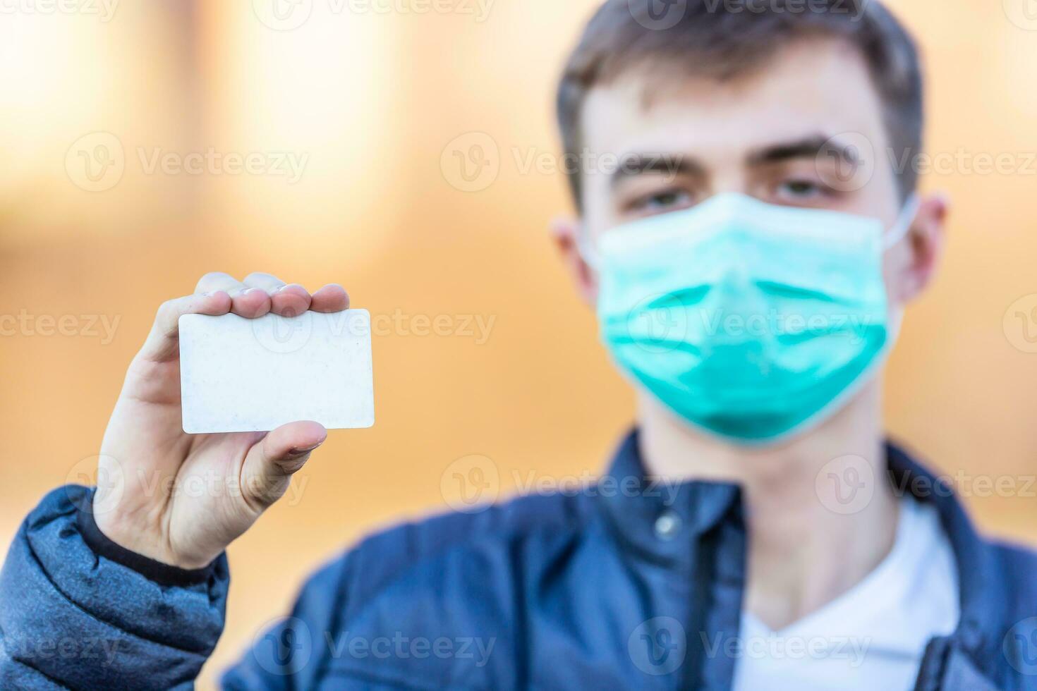 giovane uomo con protettivo maschera su il suo viso Tenere vuoto bianca carta.. protezione contro virus polvere o smog. coronavirus covid-19 concetto foto