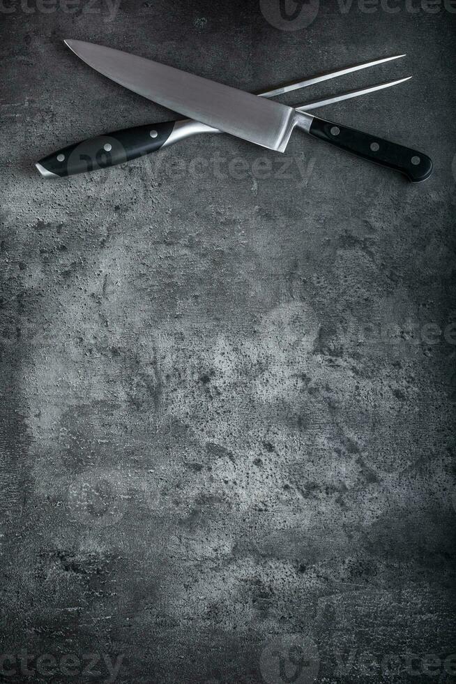 forchetta e coltello. forchetta e coltello attraversato su calcestruzzo tavola foto