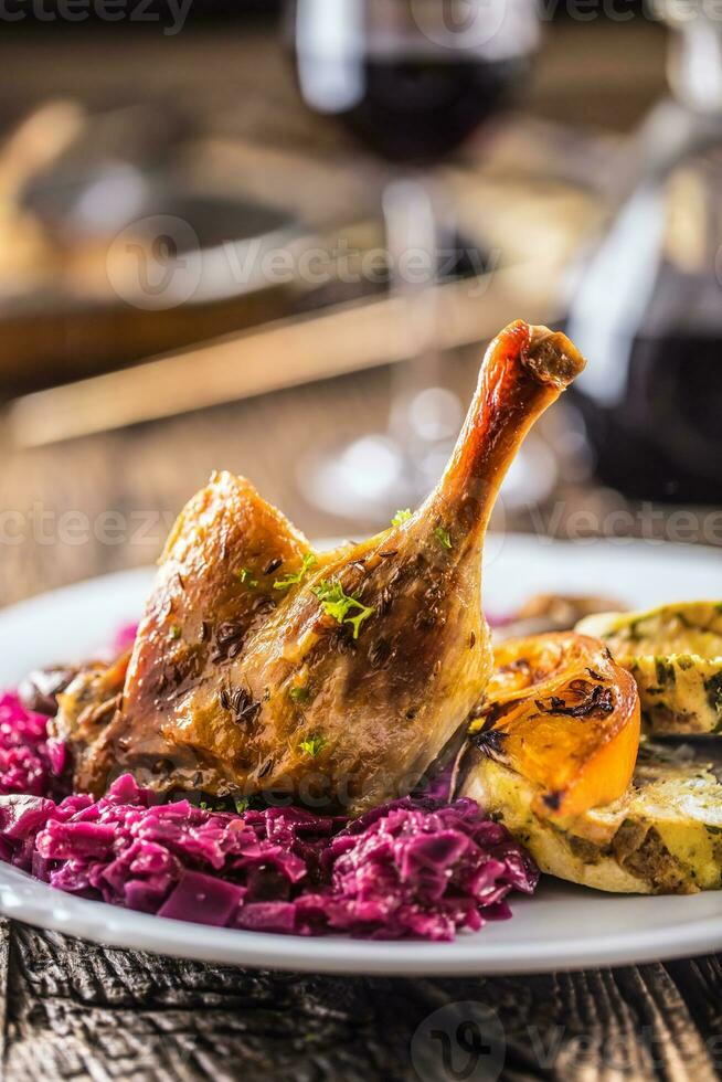 porzione di arrosto anatra gamba rosso cavolo fatti in casa Ravioli su piatto e rosso vino su il sfondo foto