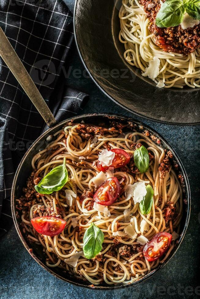 superiore di Visualizza italiano pasta spaghetti bolognese nel piatto e padella con pomodori e basilico foto