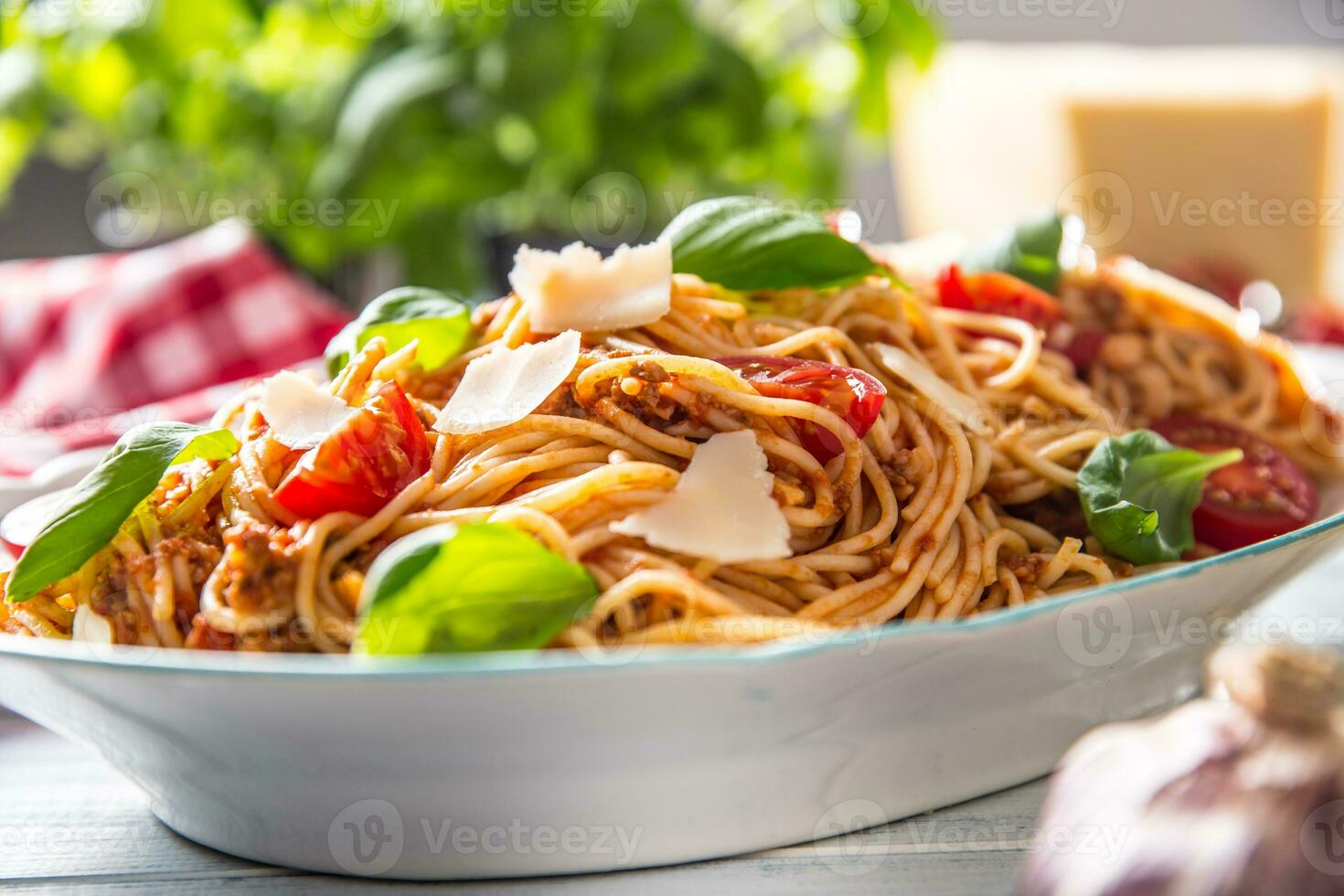 italiano pasta spaghetti bolognese nel bianca ciotola con pomodori parmigiano formaggio e basilico foto