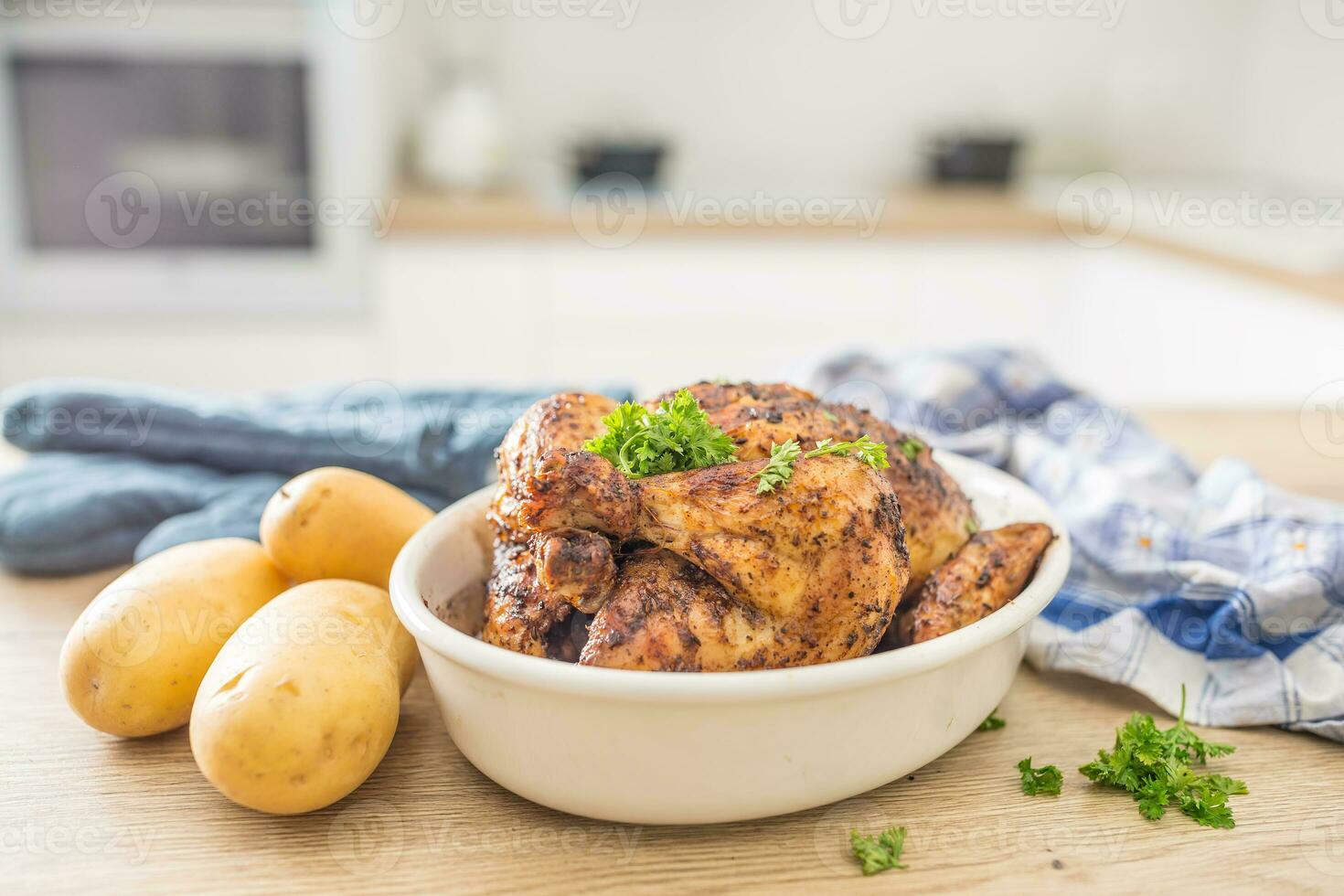 totale pollo arrostito nel bianca piatto con crudo patate su cucinato tavolo. casa interno nel il sfondo foto
