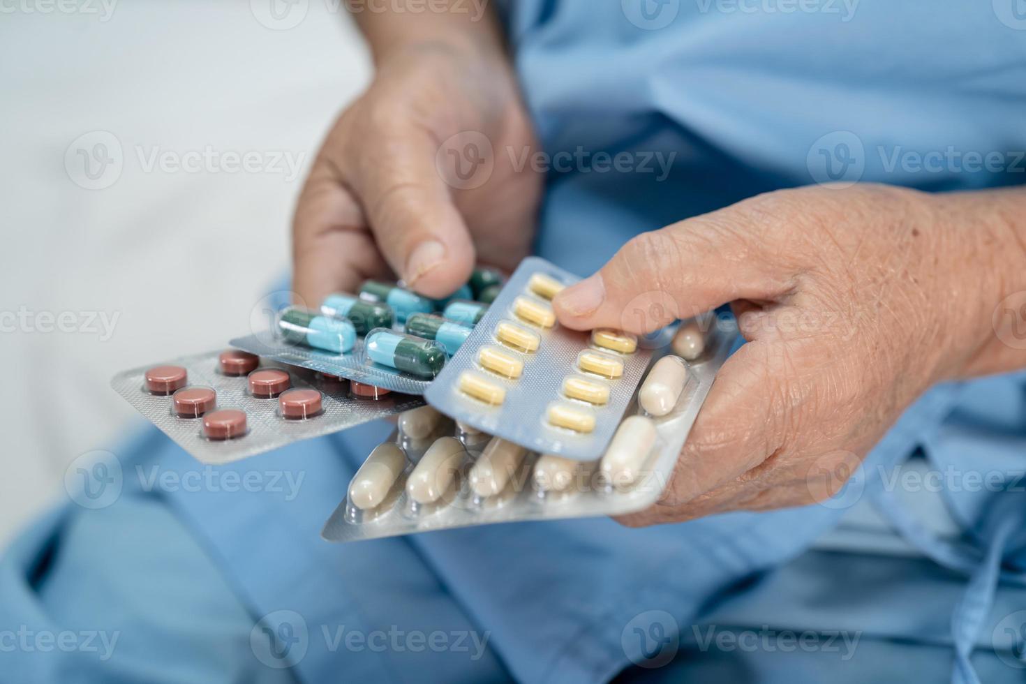 asiatico anziano o anziana signora anziana paziente in possesso di pillole di capsule di antibiotici in confezione blister per il trattamento di infezione paziente in ospedale farmacia farmacia concetto. foto