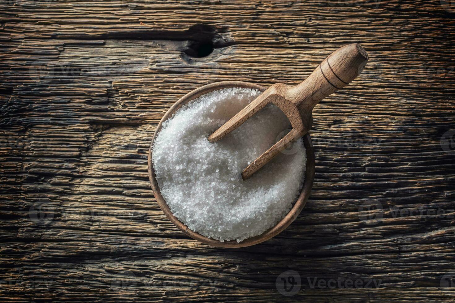 a grana grossa sale nel un' di legno ciotola con un' mestolo su un vecchio quercia tavolo foto