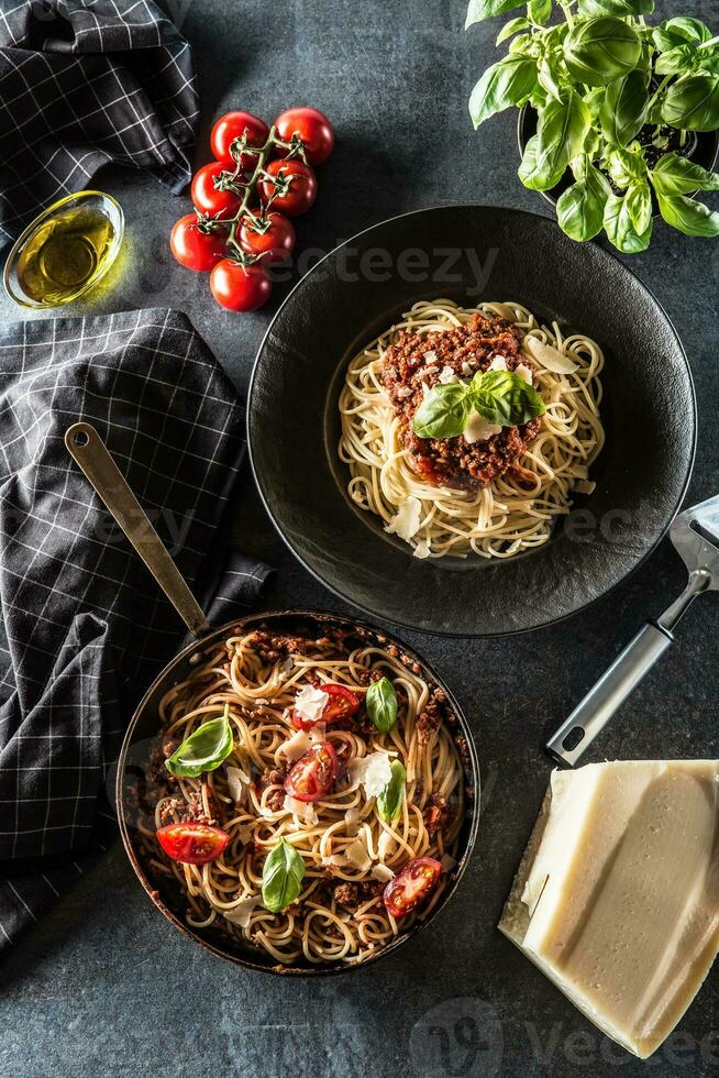 superiore di Visualizza italiano pasta spaghetti bolognese nel piatto e padella con pomodori e basilico foto