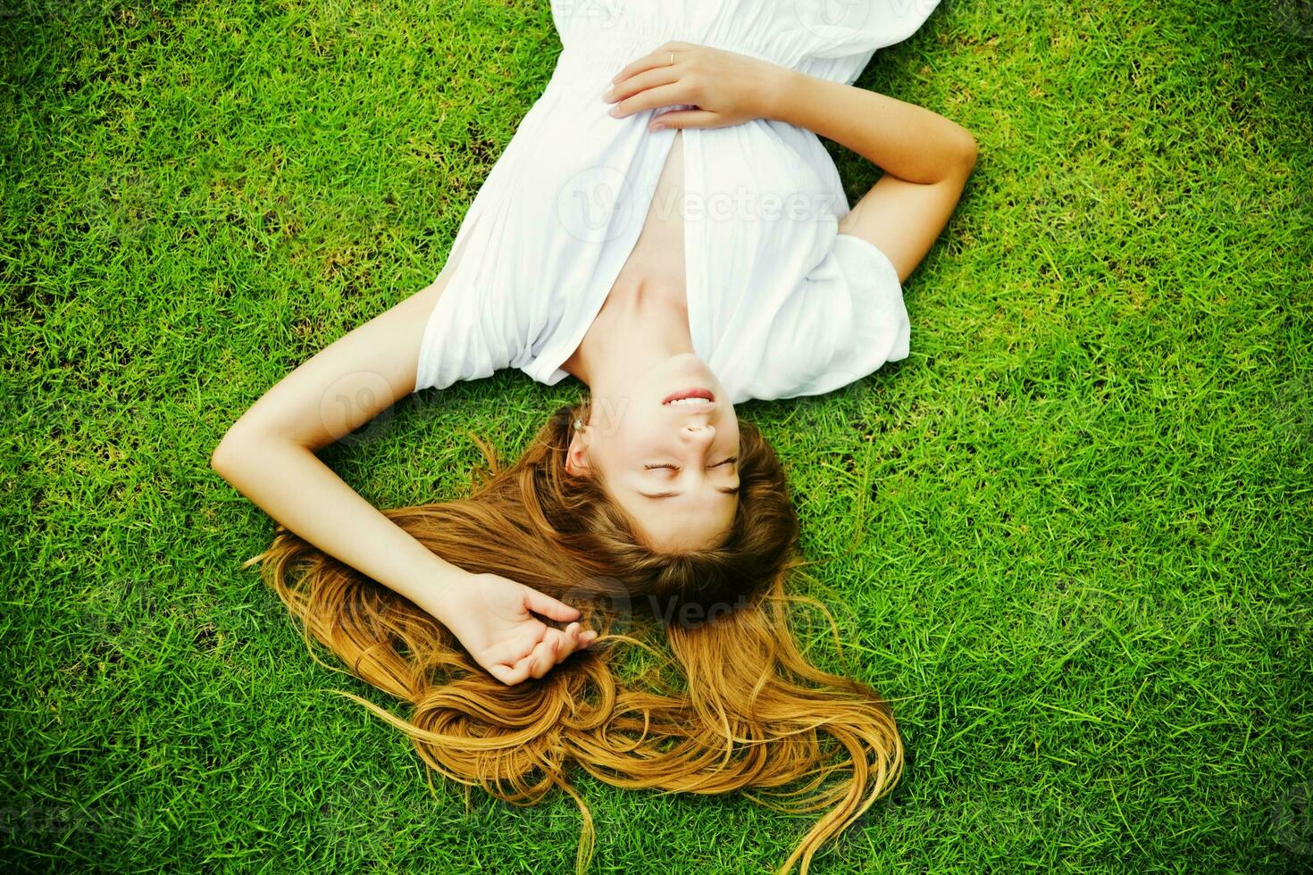 un' donna posa su il erba con sua capelli giù foto