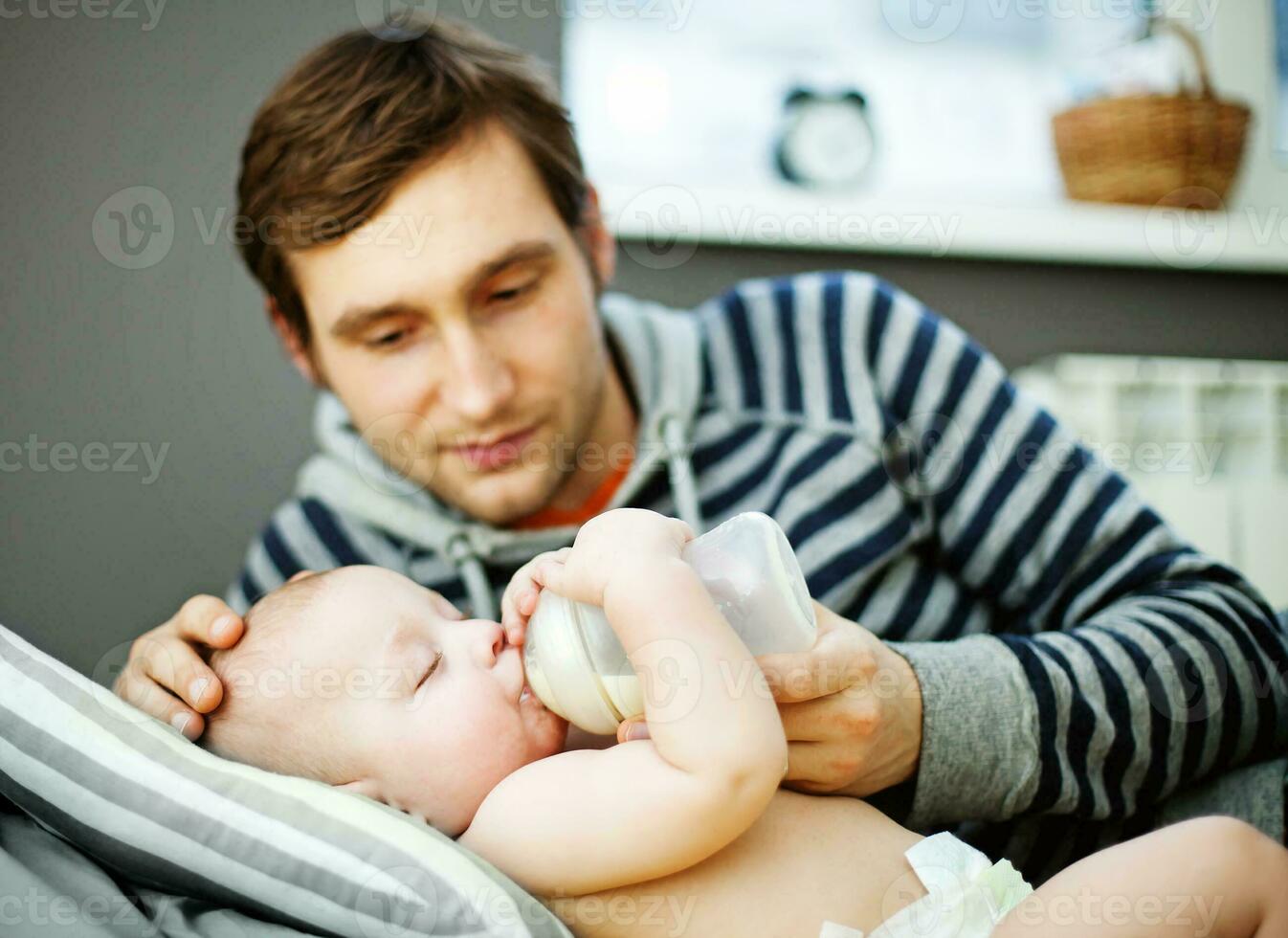 un' uomo è alimentazione il suo bambino con un' bottiglia foto