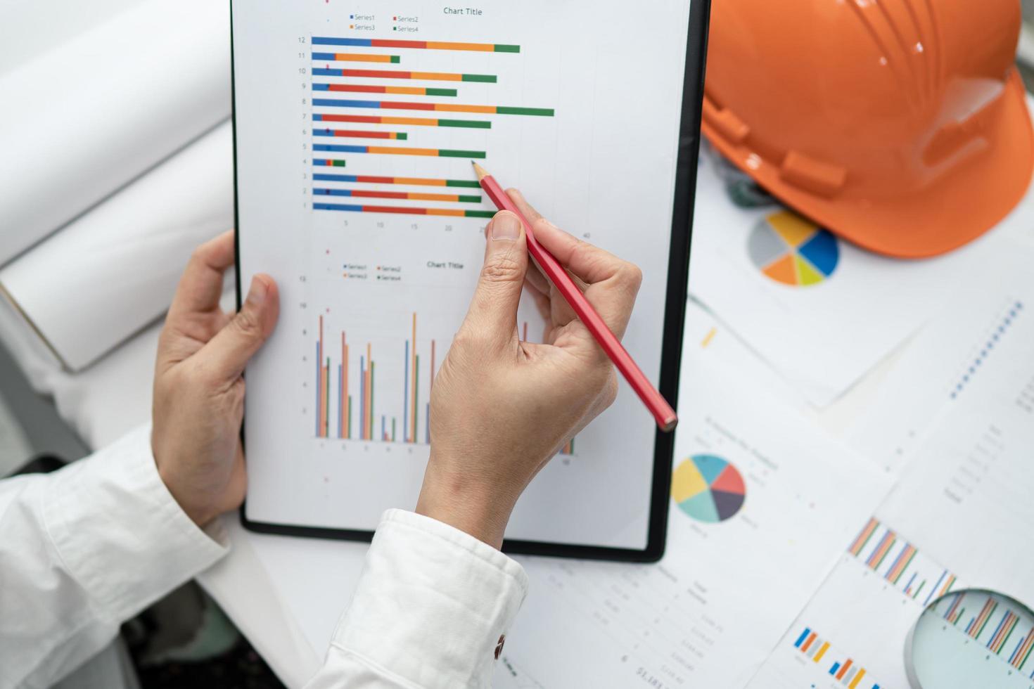 ingegnere di contabilità del progetto di lavoro con grafico e casco da costruzione in ufficio, concetto di conto di costruzione. foto