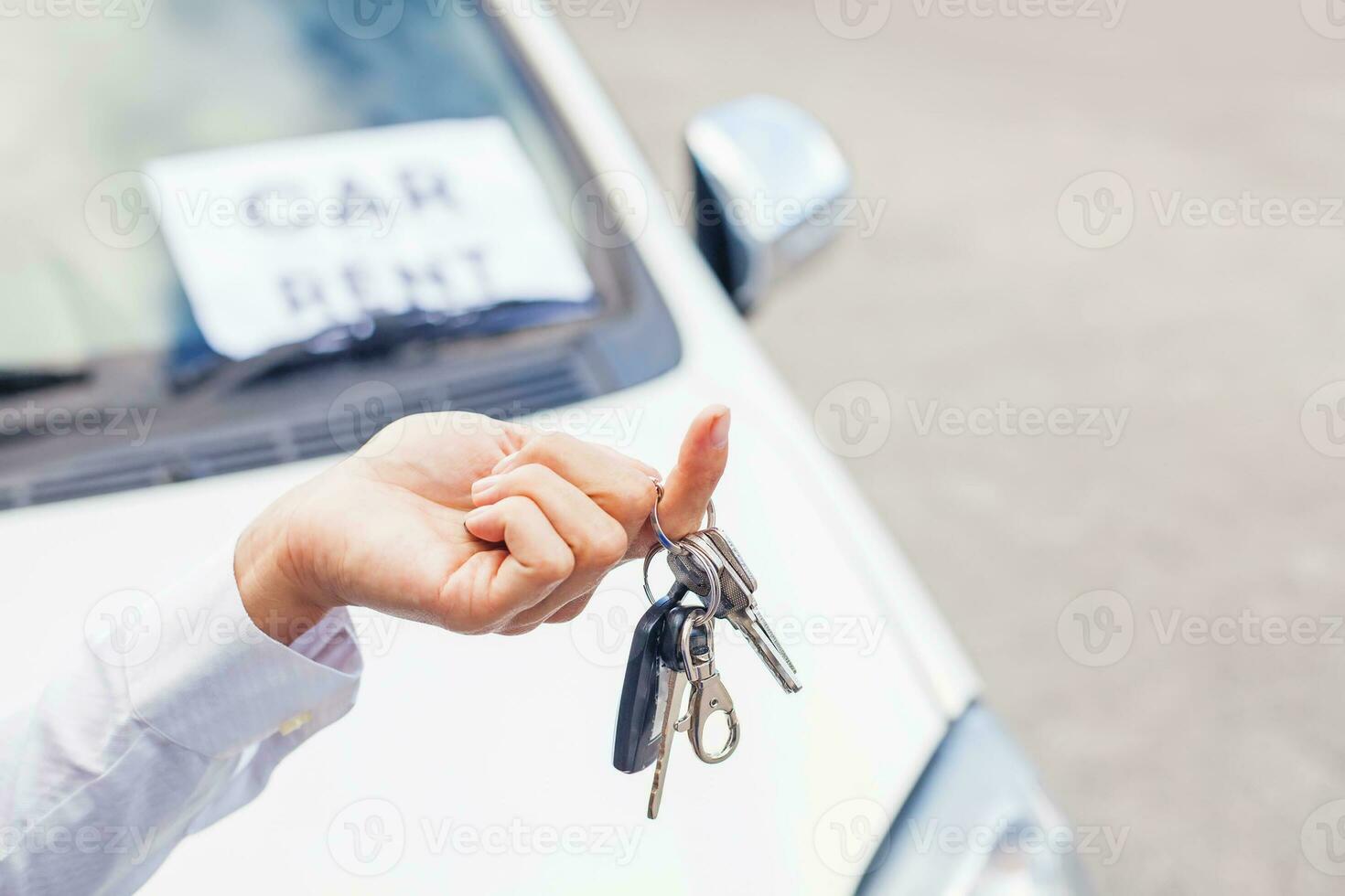 un' persona Tenere un' auto chiave e un' auto noleggio cartello foto