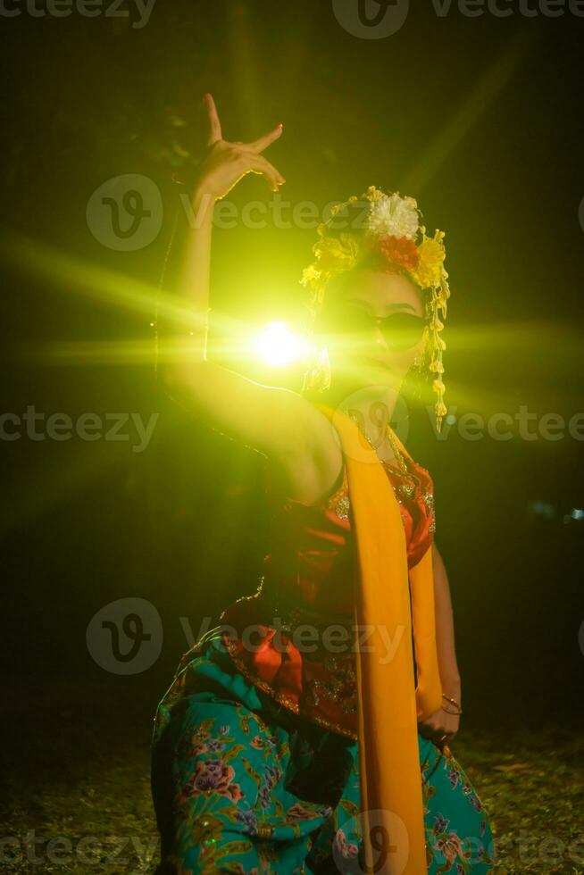 un' giavanese ballerino balli molto abilmente mentre indossare occhiali da sole su sua occhi e molto bellissimo facciale trucco foto