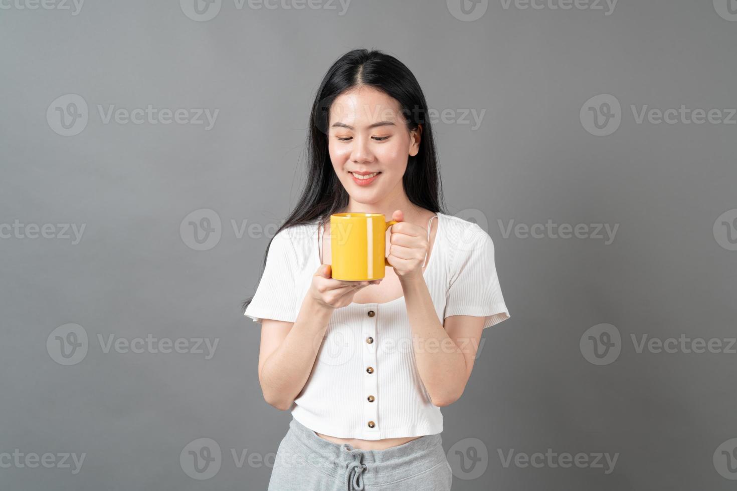 giovane donna asiatica con la faccia felice e la mano che tiene la tazza di caffè coffee foto