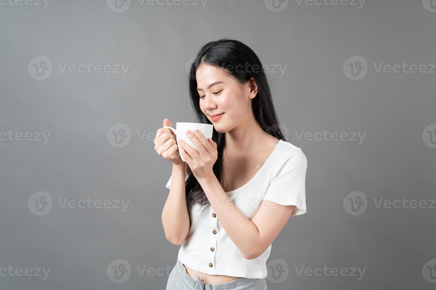 giovane donna asiatica con la faccia felice e la mano che tiene la tazza di caffè coffee foto