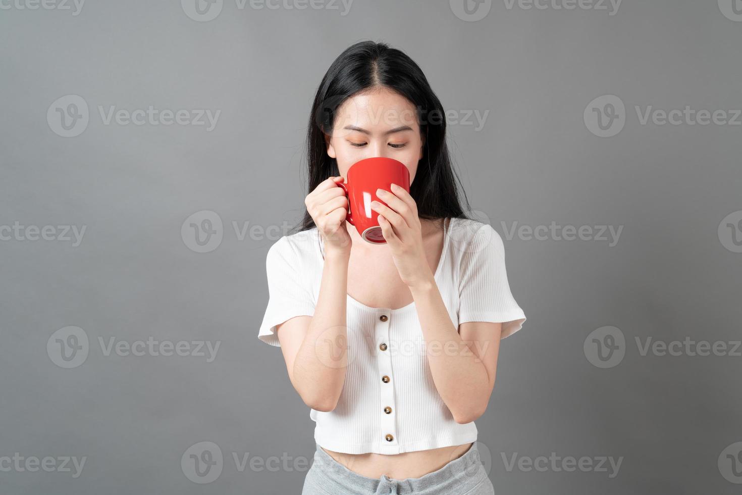 giovane donna asiatica con la faccia felice e la mano che tiene la tazza di caffè coffee foto