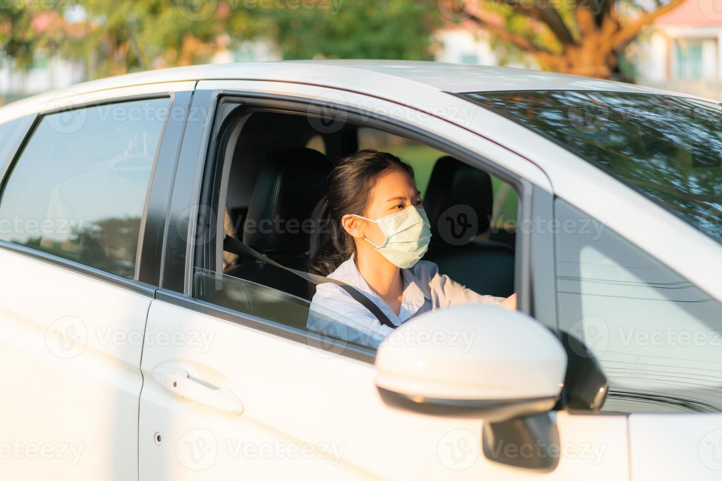 bella donna asiatica che guida un'auto indossando una maschera facciale che esce rimane in buona salute protettiva dal virus covid-19 del coronavirus foto