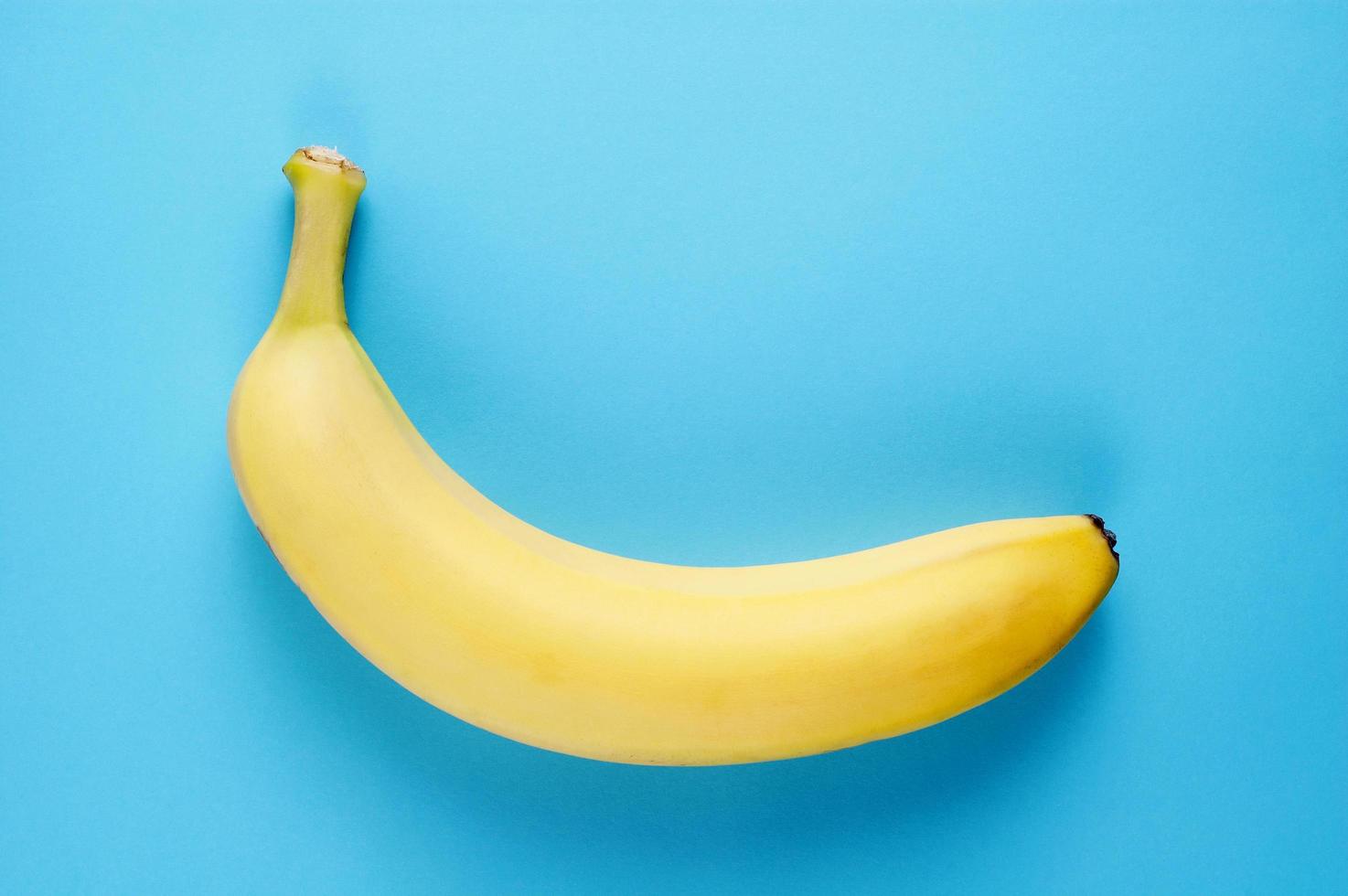 cibo semplice e sano flatlay con una banana fresca su sfondo blu foto