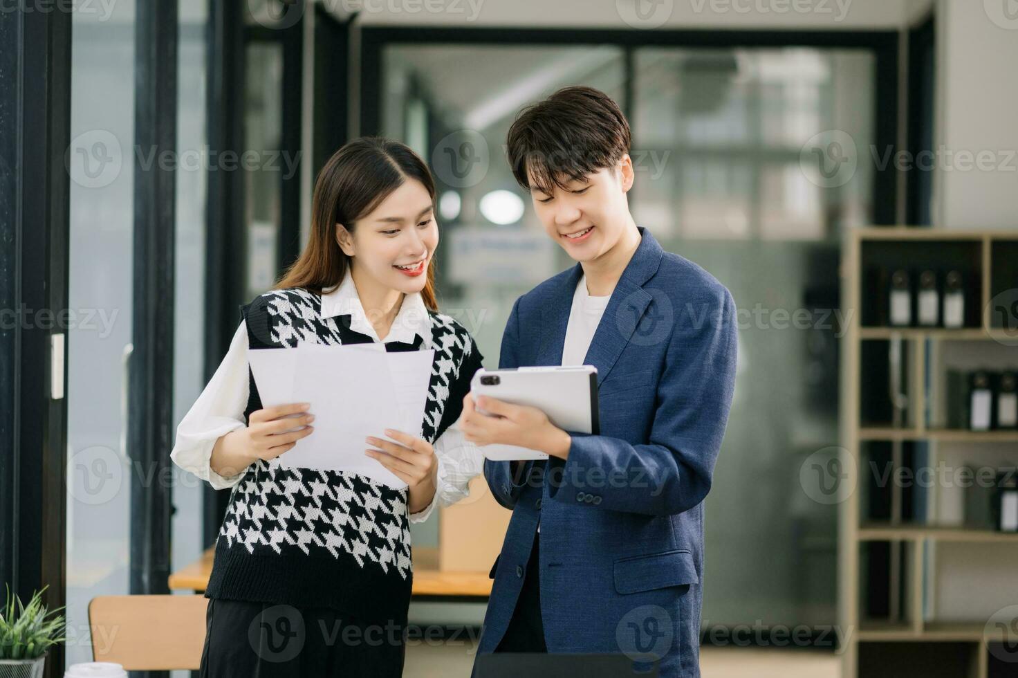 Due asiatico attività commerciale lavoratori parlando su il smartphone e utilizzando il computer portatile a il moderno ufficio. foto