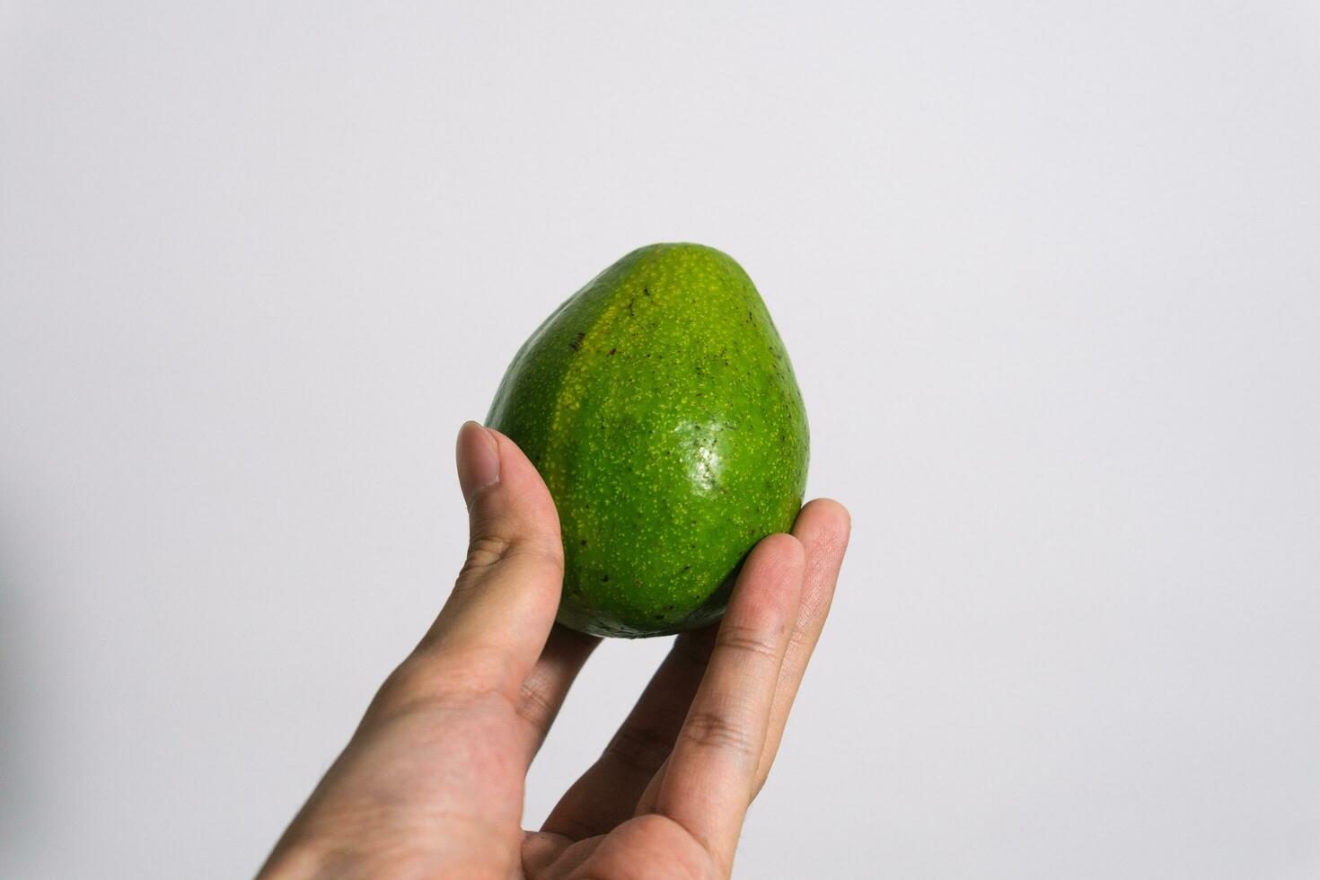 avocado frutta persea americana fresco verde isolato su bianca afferrare di mano. bianca isolato sfondo foto