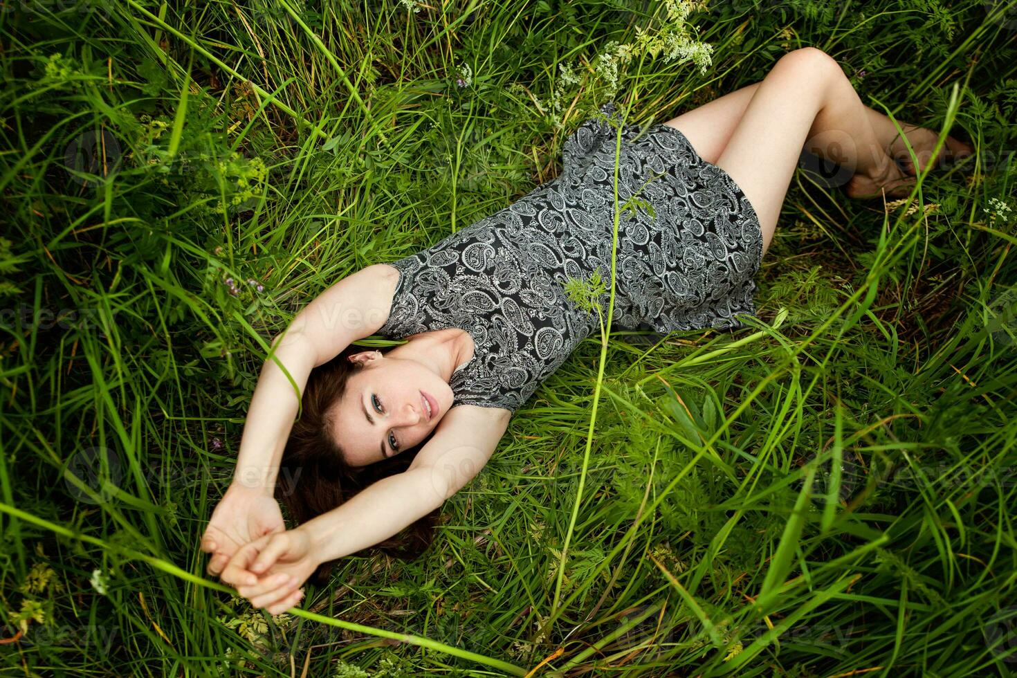 brunetta donna dire bugie su verde erba. bellezza ragazza all'aperto godendo natura e rilassamento. gratuito contento donna, superiore Visualizza foto