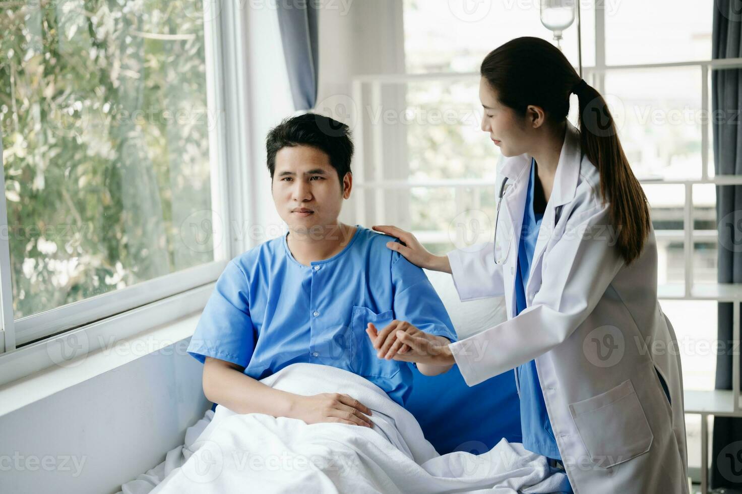 medico e giovane maschio paziente chi menzogna su il letto mentre controllo polso, consultare e spiegare con infermiera assunzione Nota nel ospedale foto