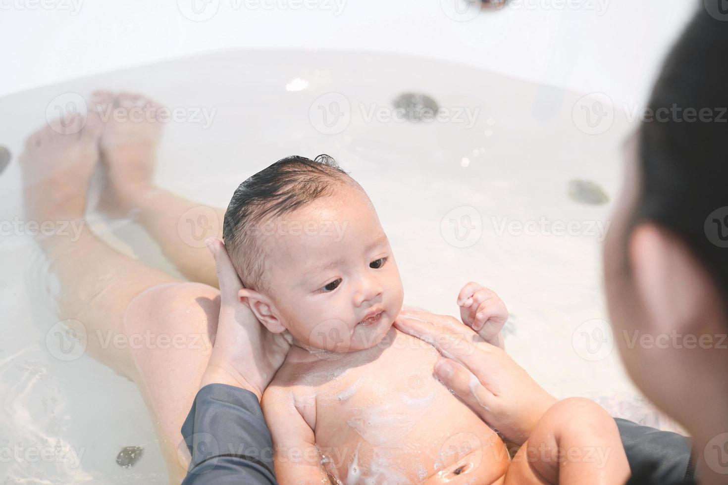 la mamma sta facendo il bagno a suo figlio nella vasca idromassaggio. foto