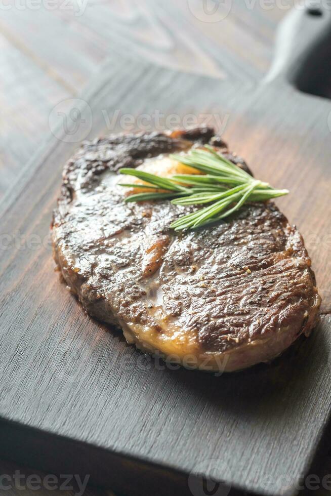 Manzo bistecca con fresco rosmarino su il di legno tavola foto