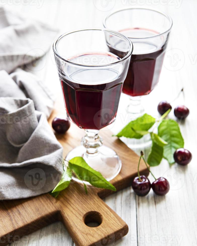 liquore di ciliegie nel bicchiere e frutta fresca foto