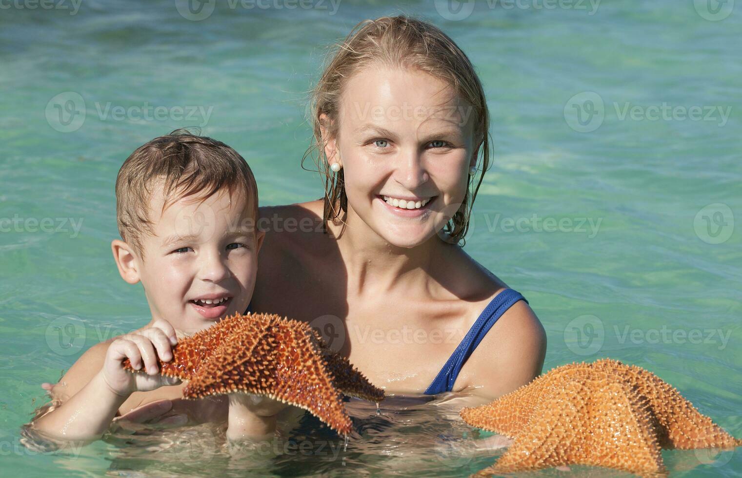 madre e figlio nel mare Tenere stella marina foto