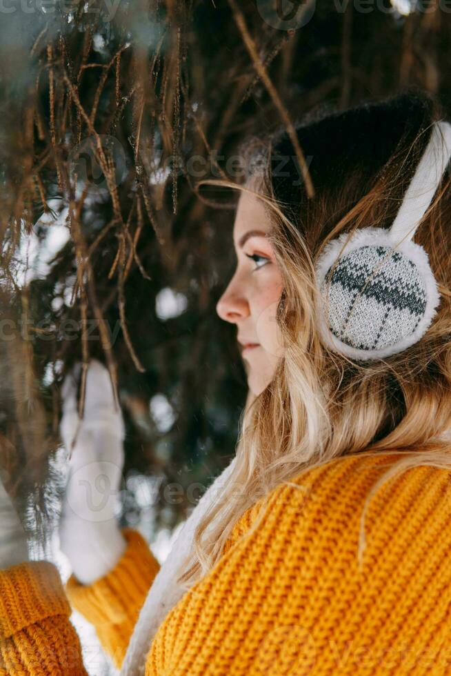 adolescente bionda nel un' giallo maglione al di fuori nel inverno. un' adolescenziale ragazza su un' camminare nel inverno Abiti nel un' nevoso foresta foto