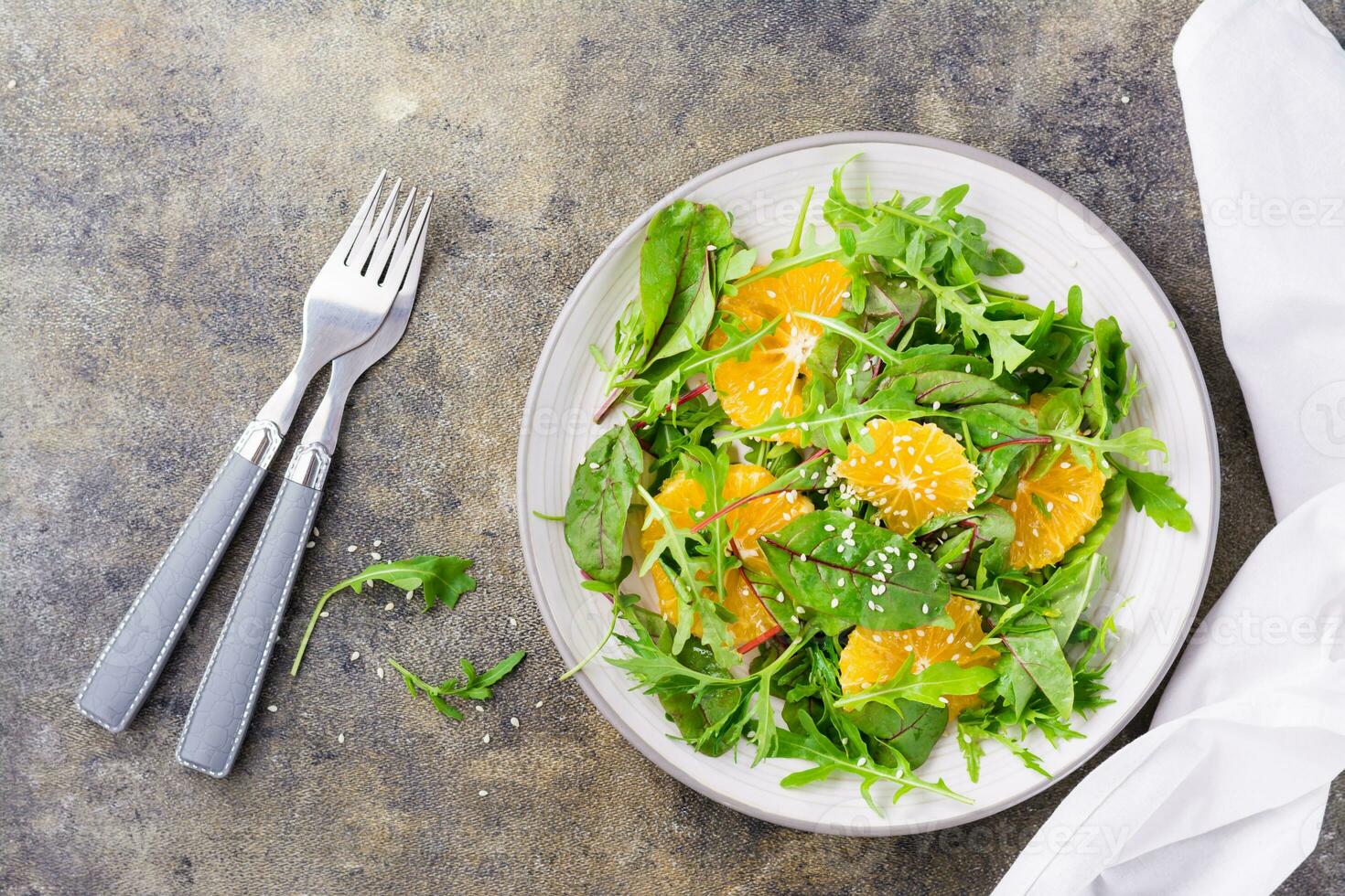 dieta vegetariano vitamina insalata di arancia pezzi e mescolare di rucola, bietola e mizun le foglie su un' piatto su il tavolo. superiore Visualizza foto