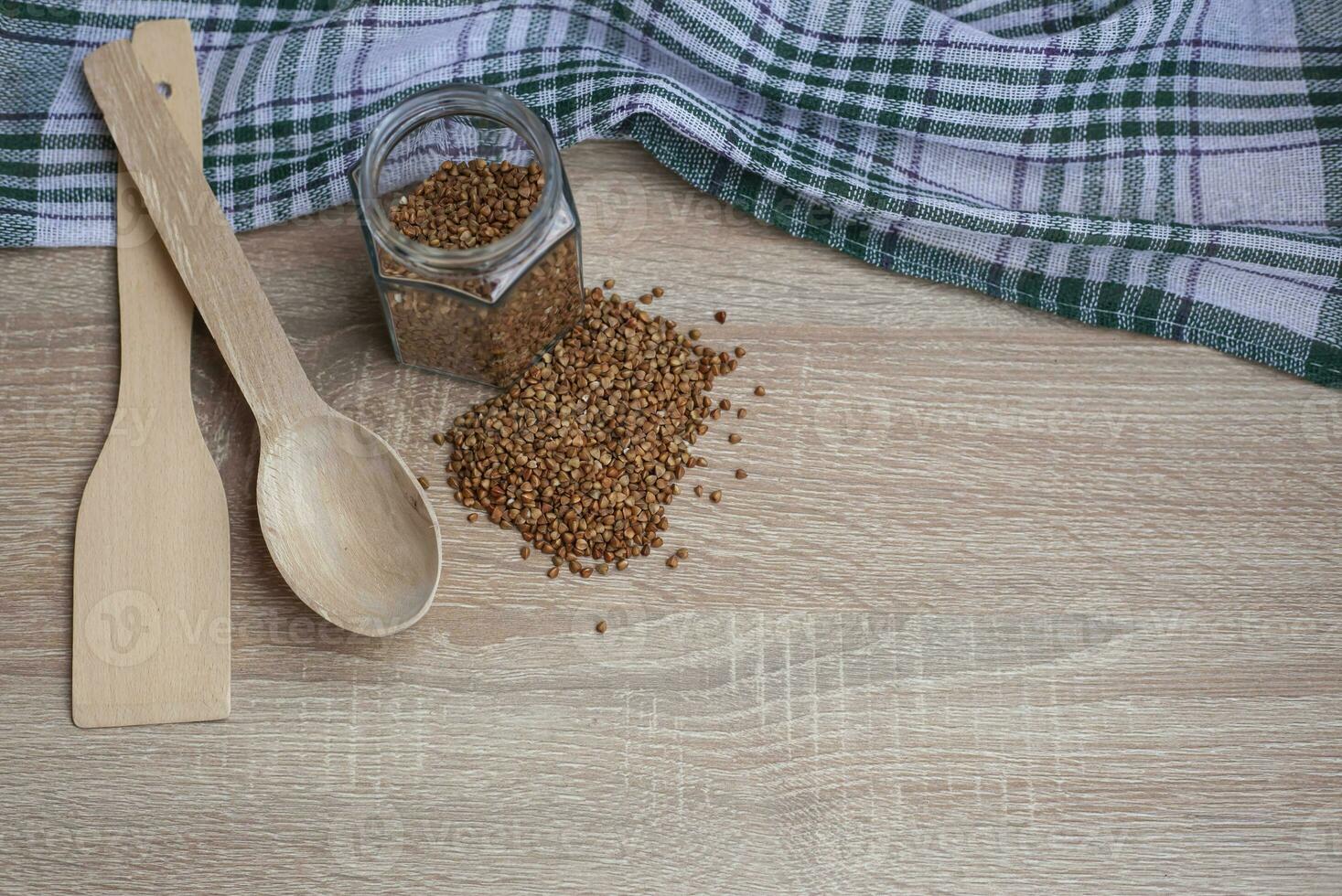 biologico crudo sparpagliato grano saraceno cereali nel un' bicchiere vaso su un' leggero sfondo. il concetto di salutare e dietetico cibo. superiore Visualizza, piatto posare foto