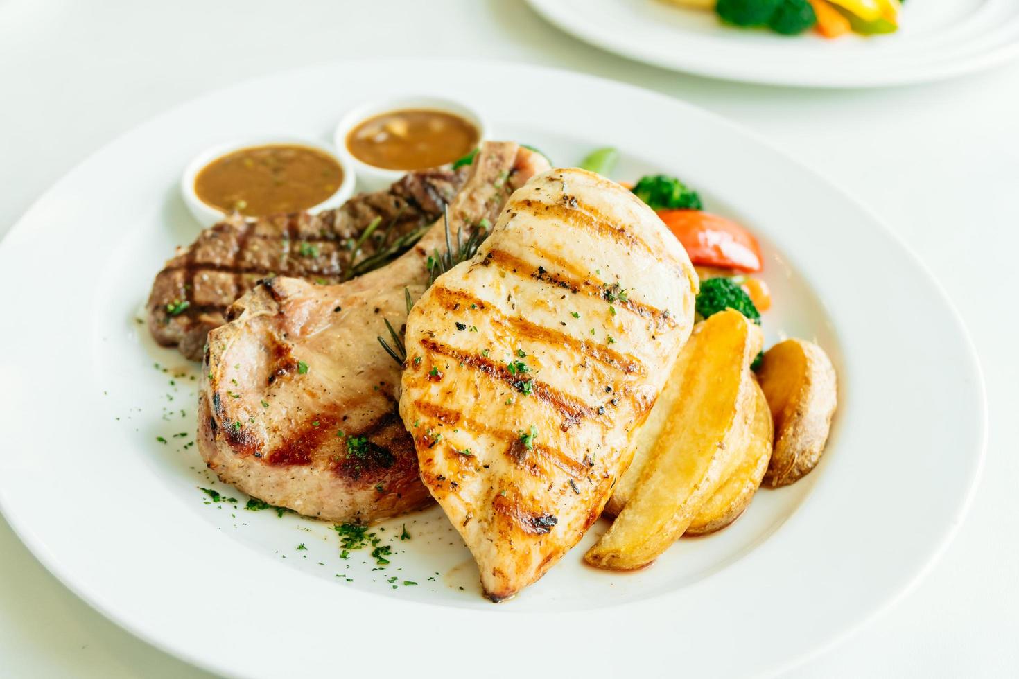 petto di pollo e braciola di maiale con bistecca di manzo e verdure foto