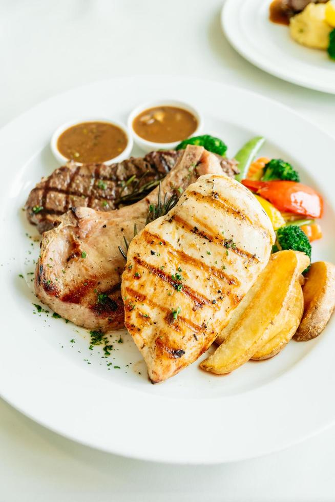 petto di pollo e braciola di maiale con bistecca di manzo e verdure foto